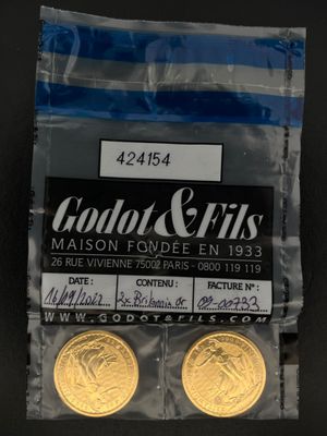 deux pièces d'or se trouvent dans un sachet en plastique posé sur une surface noire