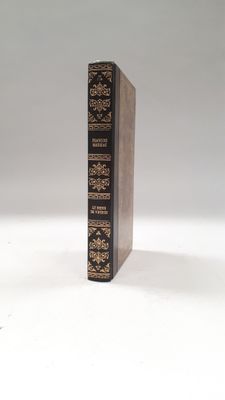un vieux livre posé sur une table blanche, à côté d'un verre