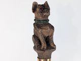 une statue représentant un chat assis sur une canne