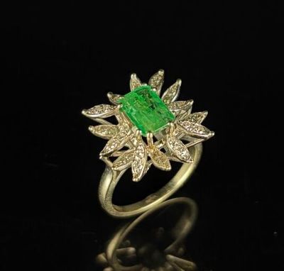 an emerald and diamond ring on a black surface