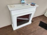 a white fireplace with a glass door in the corner of the room