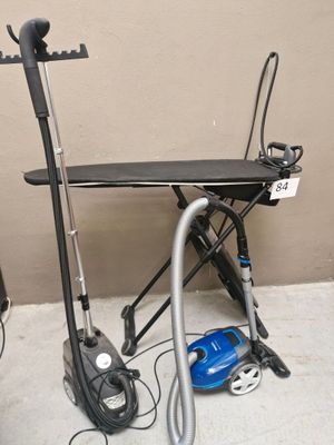 a black ironing board and a blue vacuum on the floor
