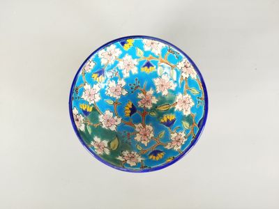 un bol bleu orné de fleurs, posé sur une table