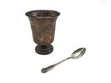 une cuillère en argent et une tasse en argent sur fond blanc