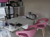 brightly colored chairs sit in front of a white table with a computer on it