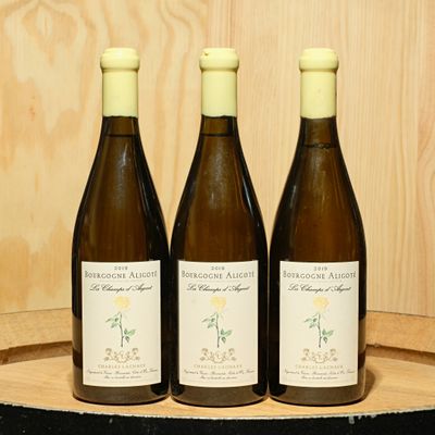 three bottles of wine sitting on top of a wooden barrel
