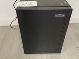 a black refrigerator sitting on top of a wooden floor next to a white wall