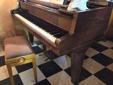 un piano dans un coin de la pièce, avec un tableau posé dessus