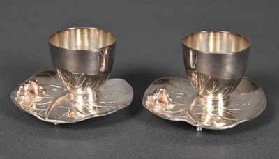 pair of silverplated cups and saucers with flowers on them