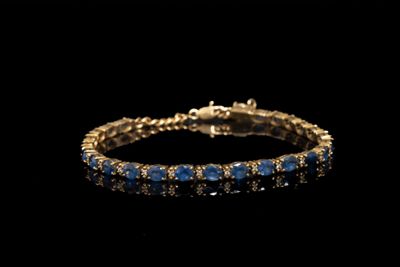 un bracelet en or orné de pierres bleues sur fond noir