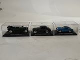 three toy cars in a display case on a table