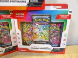 two boxes of pokemon cards sitting on top of a wooden table