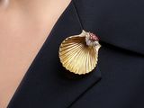 a close up of a woman wearing a gold and red broochle