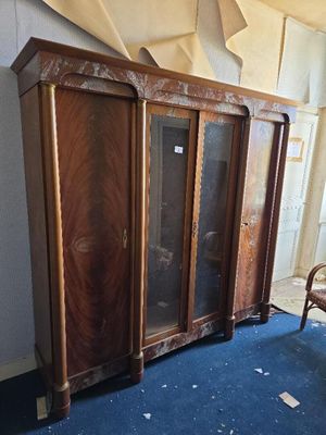 une armoire en bois avec des portes vitrées et une chaise dans une pièce