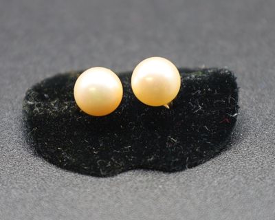 une paire de boucles d'oreilles à clous en perles jaunes sur un fond noir