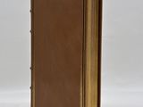 a brown book sitting on top of a table next to a white wall