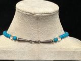a white mannequin hat with a blue beaded necklace on it