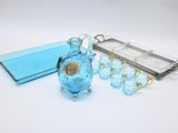 un vase en verre bleu et un plateau en argent posés sur une table blanche