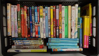 un panier en plastique noir rempli de livres et de DVD