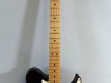 a black electric guitar sitting on top of a white wall
