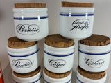 six white and blue canisters with cork lids are stacked on top of each other