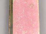 an old book with pink cover sitting on top of a table