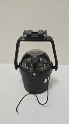 a black compass on a white table with a white background