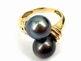 a close up of a ring with two black pearls on it