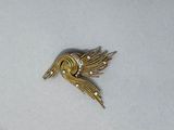 une image représentant une broche en forme d'oiseau en or ornée de perles