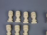 six pieces of carved ivory busts on display on a gray surface