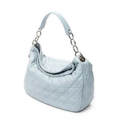 un sac à main matelassé bleu clair avec une poignée en métal sur fond blanc