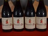 four bottles of wine are lined up on a red table