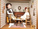 deux poupées assises dans une maison de poupées