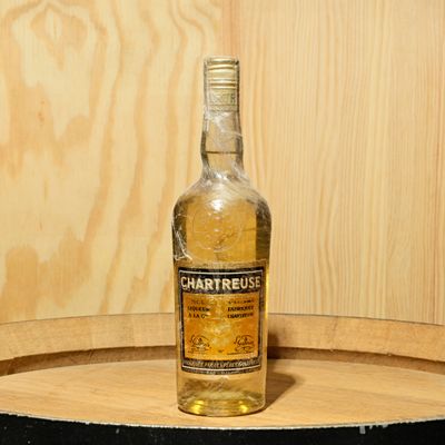 a bottle of liquor sitting on top of a wooden barrel