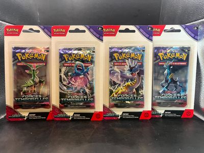 quatre paquets de cartes à collectionner Pokémon exposés dans une vitrine