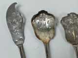 three silver spoons and a knife on a white surface