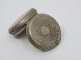 a close up of a silver pocket watch on a white surface