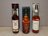 trois bouteilles d'alcool posées sur une table à côté d'une boîte