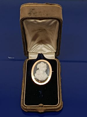 une image représentant une broche plaquée or dans un écrin posé sur un fond bleu