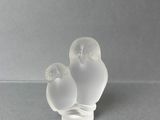 deux oiseaux en verre posés l'un sur l'autre sur une table