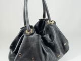 black leather handbag with gold studded handles on a white background