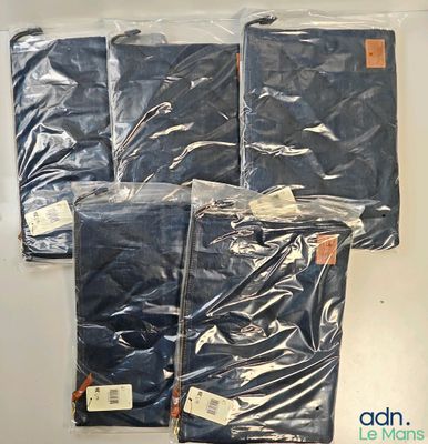 quatre paires de jeans pour homme dans des sacs en plastique, posées sur une surface blanche