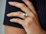 the woman is wearing a black shirt and a pearl ring