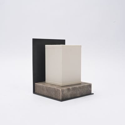 un vase blanc posé sur une boîte noire, sur une surface blanche