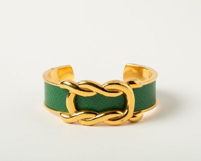 a close up of a gold ring with a green leather band