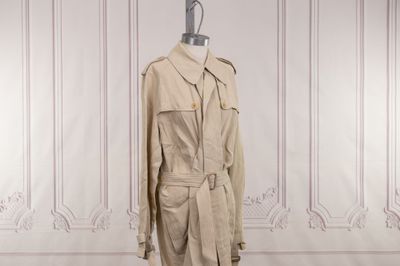 un trench-coat beige posé sur un mannequin dans une pièce blanche