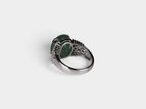 a close up of a ring on a white surface with a green stone
