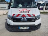 La camionnette est garée sur le chemin de terre devant un immeuble.