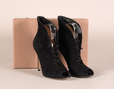 des bottines noires en daim à lacets, posées devant une boîte en carton