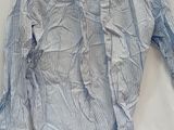 a blue and white shirt on a hanger on a bed